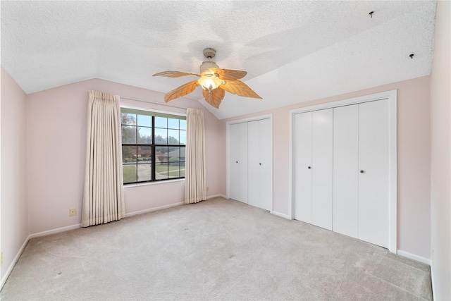 unfurnished bedroom with a textured ceiling, ceiling fan, light colored carpet, and vaulted ceiling