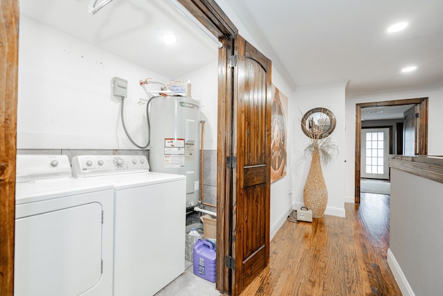 washroom featuring light hardwood / wood-style floors, washing machine and dryer, electric water heater, and ornamental molding