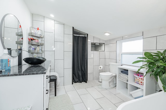 bathroom with tile patterned floors, vanity, tile walls, and vaulted ceiling