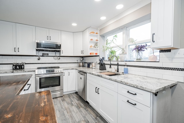 kitchen with hardwood / wood-style floors, wood counters, sink, white cabinetry, and stainless steel appliances