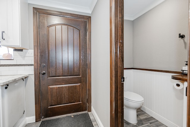 bathroom with backsplash, toilet, and crown molding