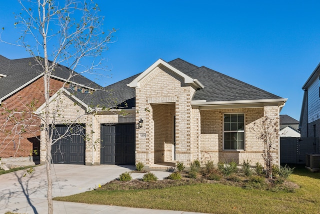 view of front of property with a garage, a front yard, and central AC