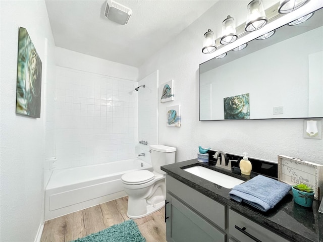 full bathroom featuring vanity, wood-type flooring, tiled shower / bath combo, and toilet