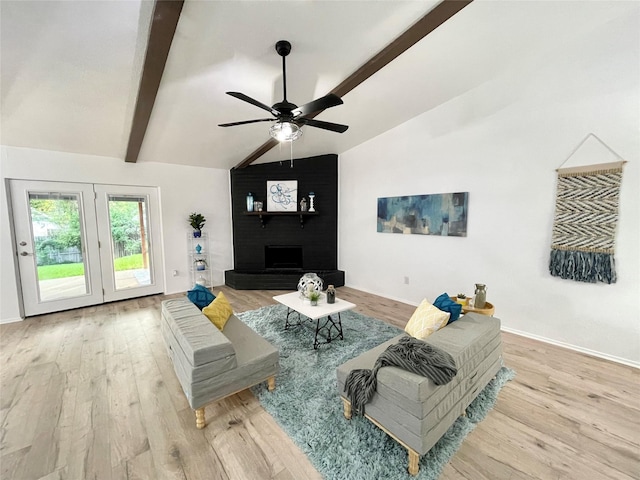 living room with lofted ceiling with beams, a large fireplace, ceiling fan, and light hardwood / wood-style flooring