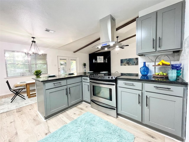 kitchen featuring backsplash, island exhaust hood, kitchen peninsula, stainless steel electric range, and ceiling fan with notable chandelier