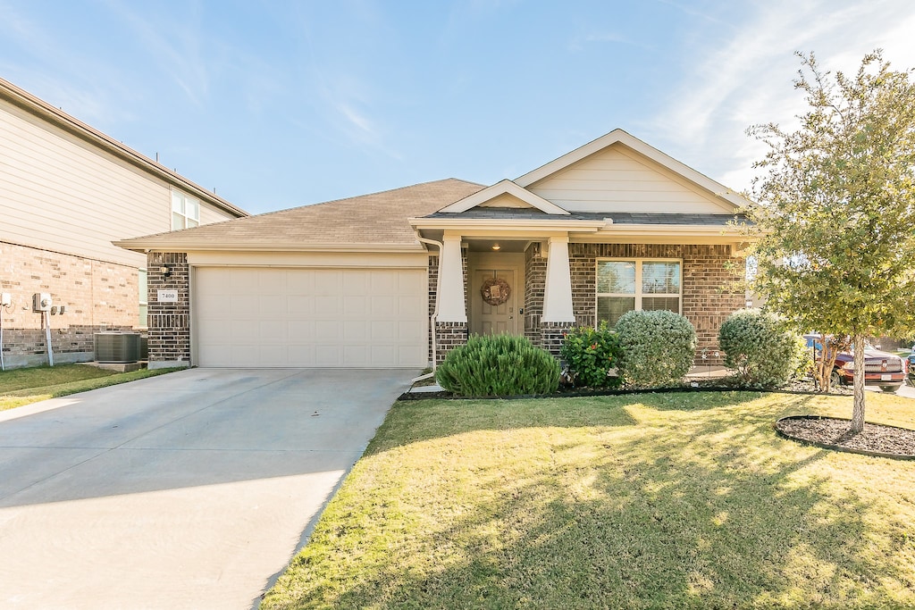 view of front of house with central AC, a garage, and a front lawn