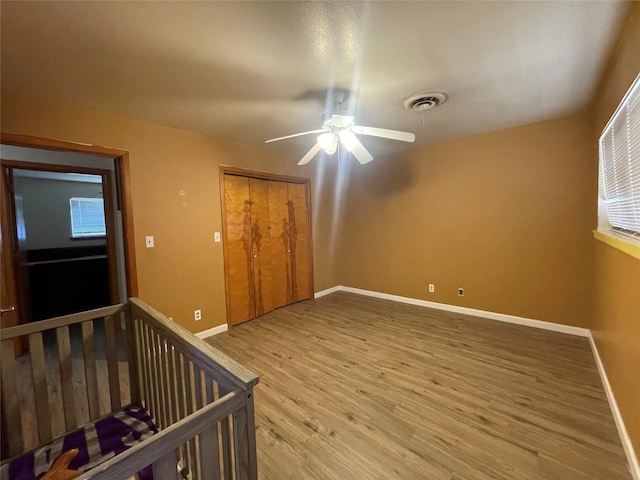 unfurnished bedroom featuring wood-type flooring, ceiling fan, and a closet