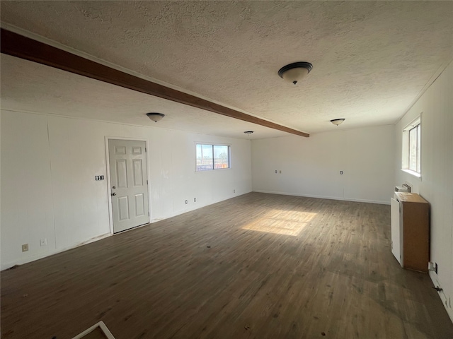 unfurnished living room with beam ceiling, a wealth of natural light, dark hardwood / wood-style floors, and a textured ceiling