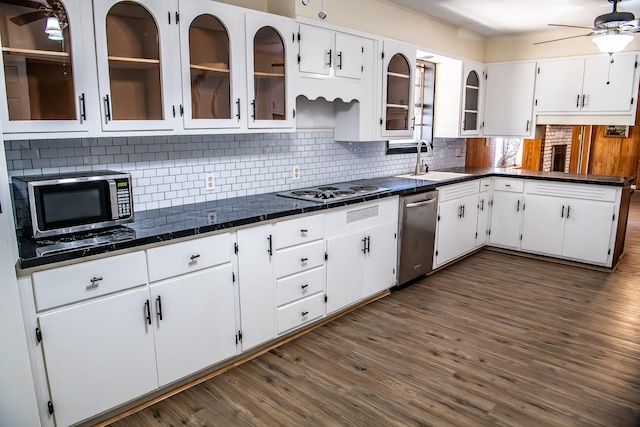 kitchen with stainless steel appliances, decorative backsplash, a ceiling fan, white cabinetry, and a sink