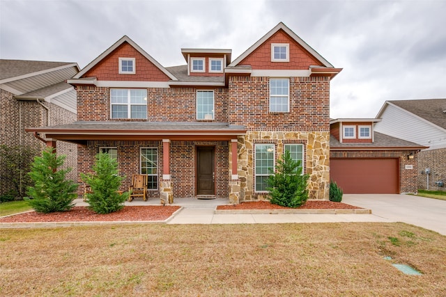 craftsman-style house featuring a garage, covered porch, and a front yard