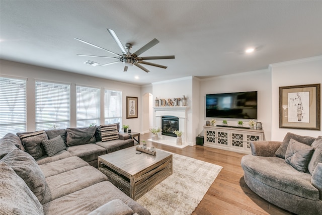 living room featuring ceiling fan, light wood-type flooring, and ornamental molding