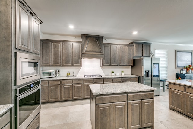 kitchen featuring dark brown cabinets, a kitchen island, crown molding, and stainless steel appliances