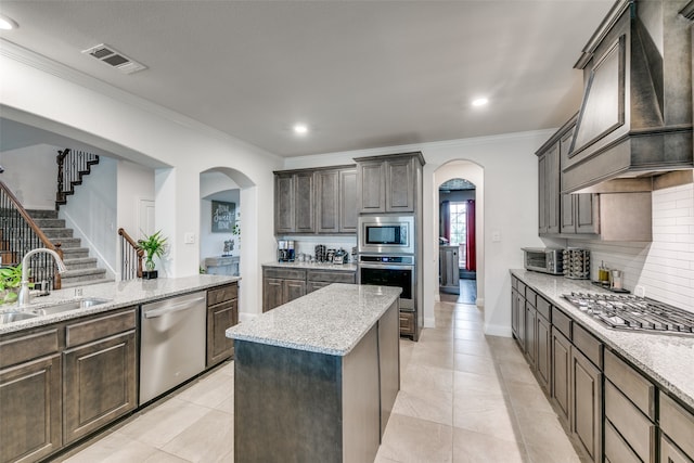 kitchen featuring custom exhaust hood, sink, ornamental molding, appliances with stainless steel finishes, and a kitchen island