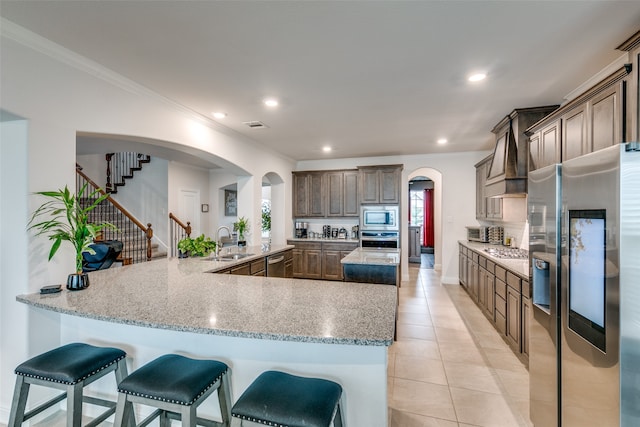 kitchen featuring sink, stainless steel appliances, crown molding, a breakfast bar area, and light tile patterned floors