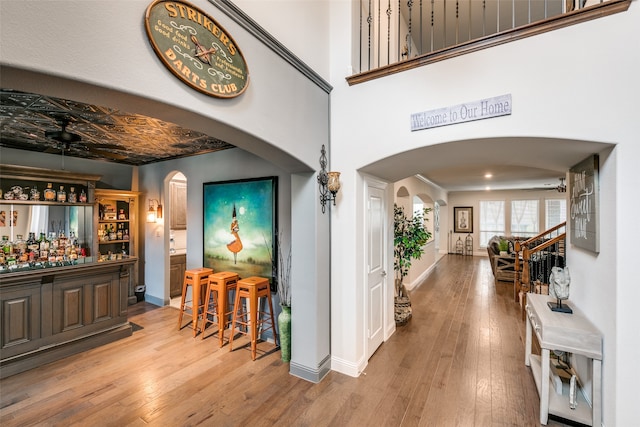 entryway with hardwood / wood-style flooring, ceiling fan, a high ceiling, and bar