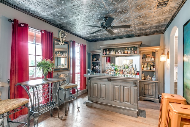 bar with ceiling fan, ornamental molding, and light hardwood / wood-style flooring