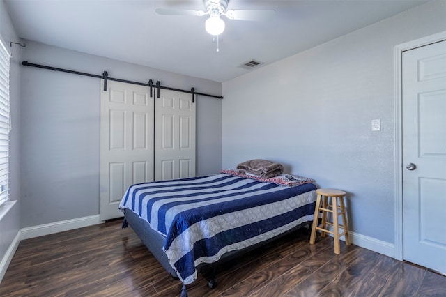 bedroom featuring a barn door, a closet, ceiling fan, and dark wood-type flooring