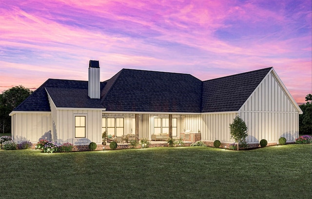 back house at dusk featuring a lawn