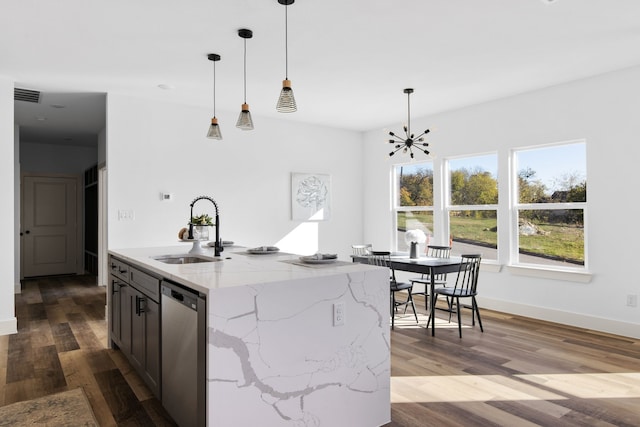 kitchen with stainless steel dishwasher, light stone countertops, wood-type flooring, and sink