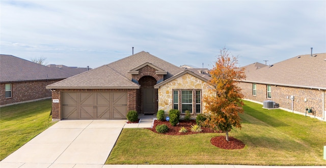 view of front of home with a front yard, central AC unit, and a garage