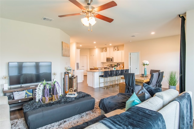 living room with ceiling fan and dark wood-type flooring