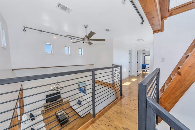 corridor featuring a notable chandelier, light hardwood / wood-style flooring, and track lighting