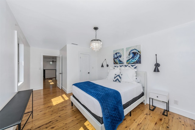 bedroom with wood-type flooring and an inviting chandelier