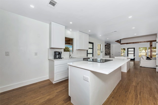 kitchen with sink, dark wood-type flooring, black electric stovetop, white cabinets, and a kitchen island