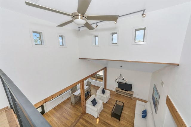 living room with rail lighting, ceiling fan with notable chandelier, and light hardwood / wood-style flooring