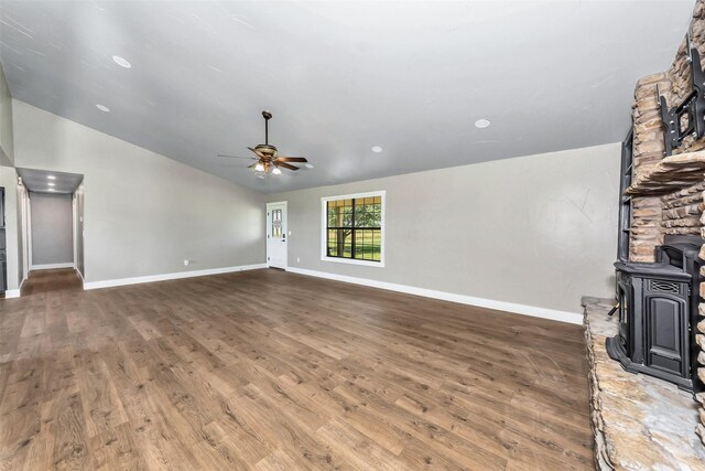 unfurnished living room featuring vaulted ceiling, a wood stove, ceiling fan, and dark wood-type flooring