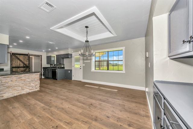 kitchen featuring a chandelier, dark hardwood / wood-style flooring, a barn door, and gray cabinets