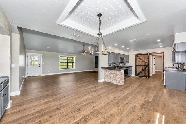 kitchen featuring a barn door, pendant lighting, gray cabinetry, and wood-type flooring