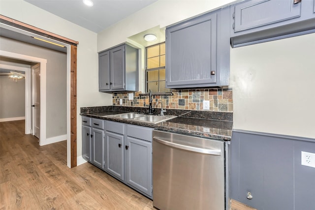 kitchen featuring decorative backsplash, stainless steel dishwasher, gray cabinetry, sink, and light hardwood / wood-style flooring