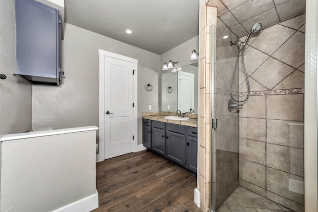 bathroom with vanity, wood-type flooring, and tiled shower