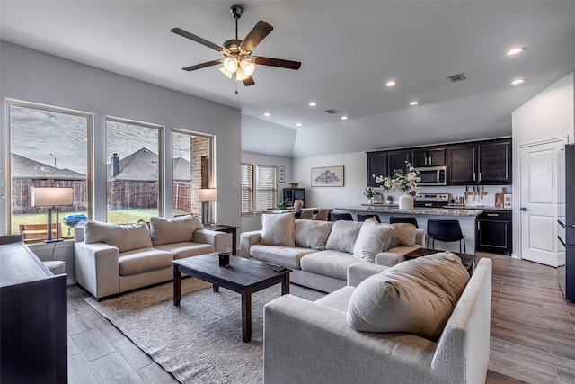 living room with vaulted ceiling, light hardwood / wood-style floors, and ceiling fan