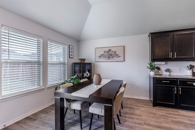 dining space featuring light wood-type flooring and vaulted ceiling