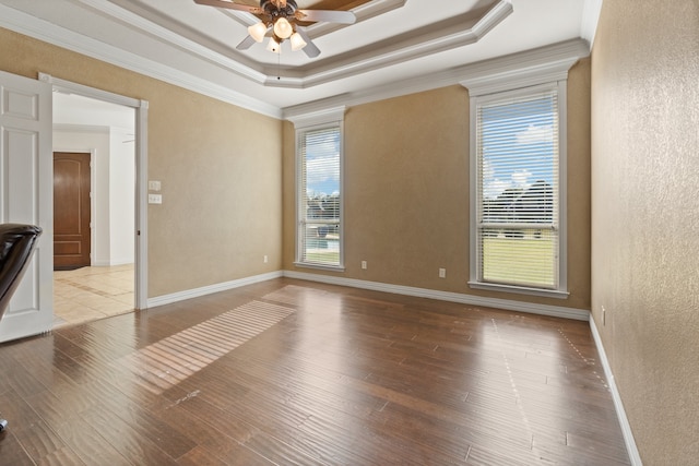 unfurnished room with light wood-type flooring, a raised ceiling, ceiling fan, and ornamental molding