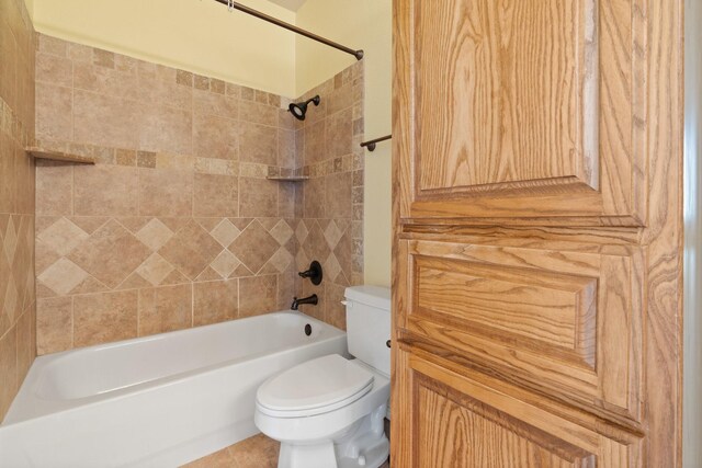 bathroom featuring tile patterned flooring, tiled shower / bath combo, and toilet