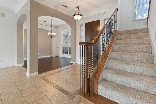 entryway with a healthy amount of sunlight, light wood-type flooring, crown molding, and an inviting chandelier