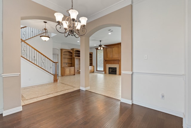 unfurnished living room with wood-type flooring, ceiling fan with notable chandelier, and crown molding