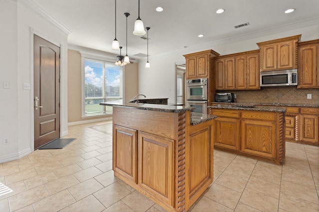 kitchen featuring backsplash, stainless steel appliances, crown molding, hanging light fixtures, and an island with sink