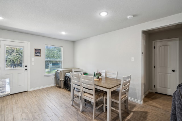 dining space with a textured ceiling and light hardwood / wood-style flooring