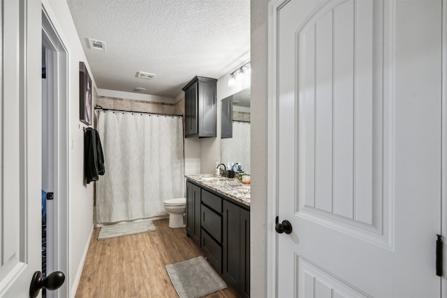 bathroom featuring a shower with curtain, vanity, a textured ceiling, hardwood / wood-style floors, and toilet