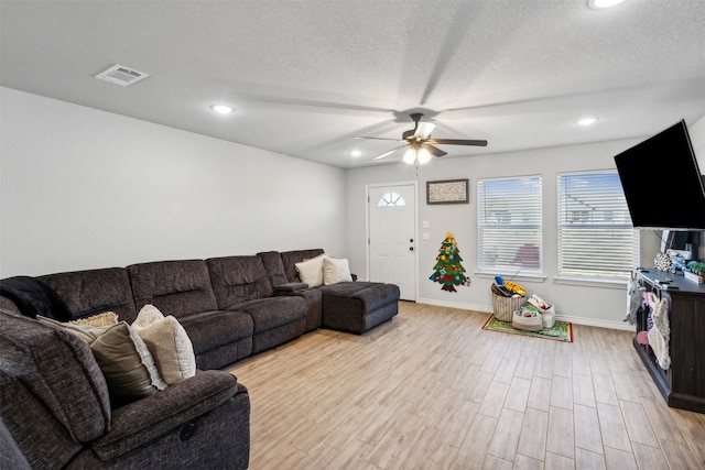 living room with a textured ceiling, light hardwood / wood-style floors, and ceiling fan