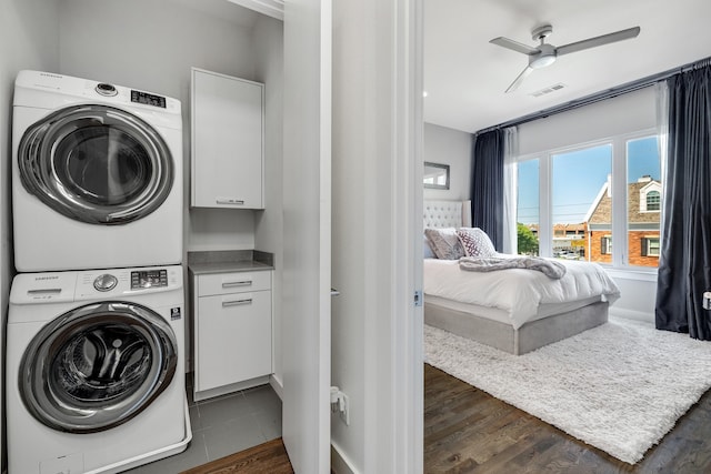 washroom featuring ceiling fan, dark hardwood / wood-style flooring, cabinets, and stacked washer / drying machine