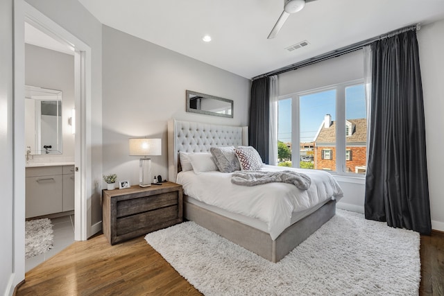 bedroom featuring ceiling fan, ensuite bathroom, and dark hardwood / wood-style floors