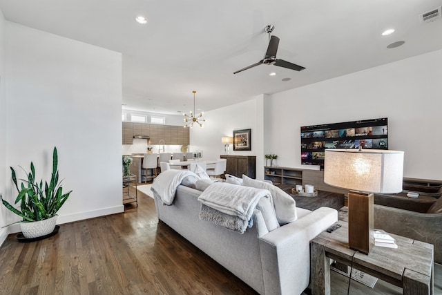 living room with ceiling fan with notable chandelier and dark hardwood / wood-style floors