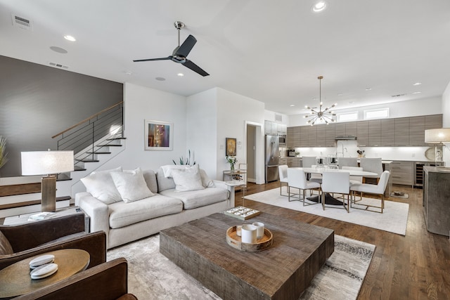 living room with ceiling fan with notable chandelier, light wood-type flooring, and beverage cooler