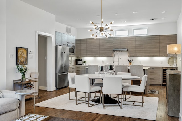 dining area with dark hardwood / wood-style floors, an inviting chandelier, and beverage cooler