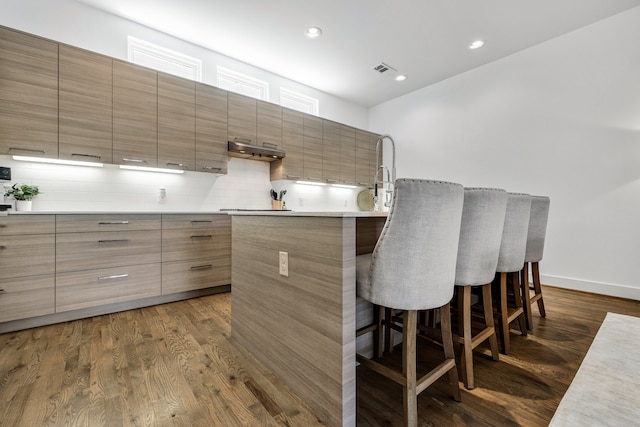 interior space featuring backsplash, a breakfast bar, and dark hardwood / wood-style floors